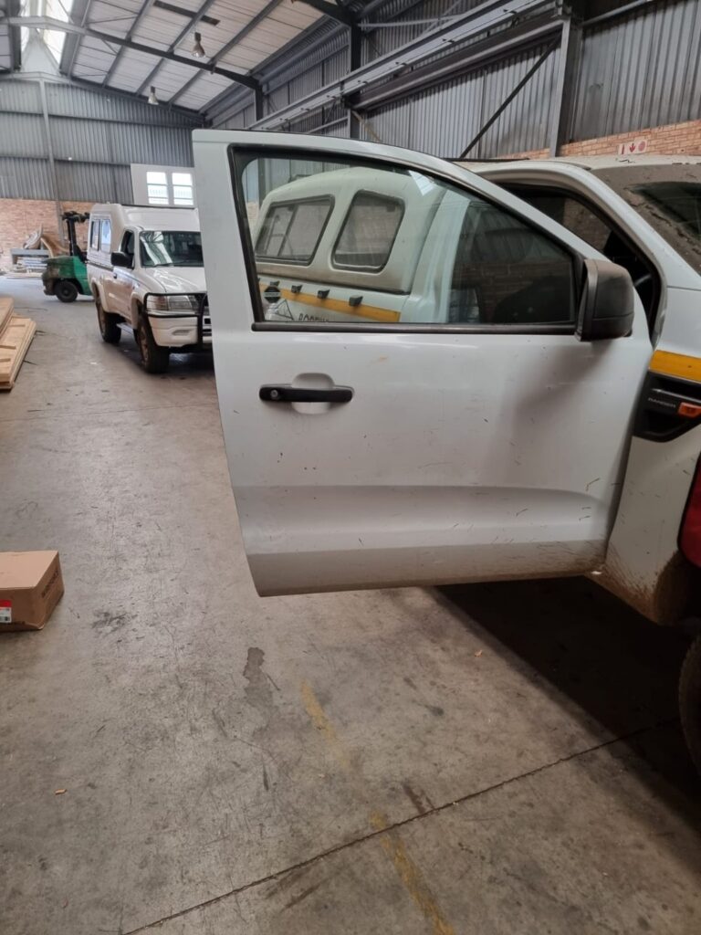 Two white business bakkies inside an industrial building