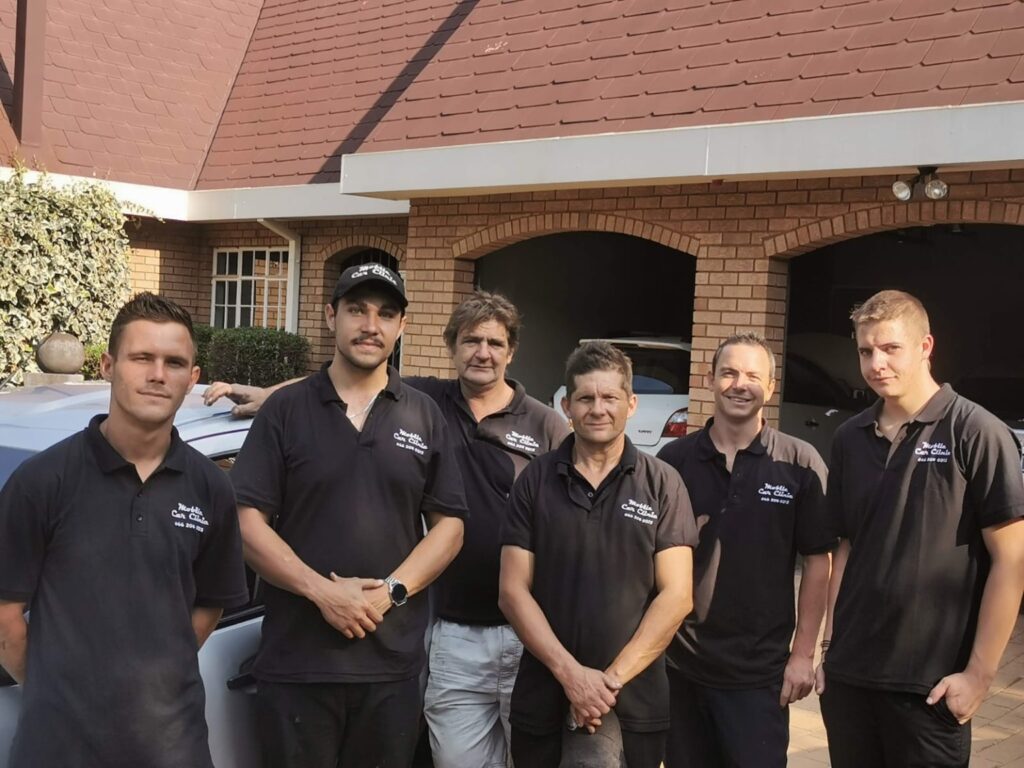 Group photograph of six people wearing Mobile Car Clinic shirts