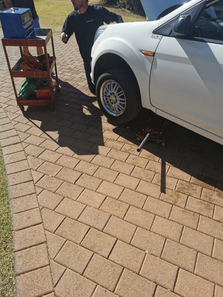 Mechanical work on a white hatchback outdoors