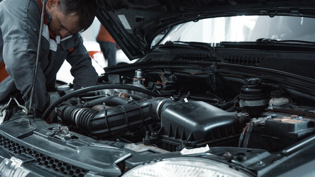 Illustrative photograph of an automotive professional inspecting an engine